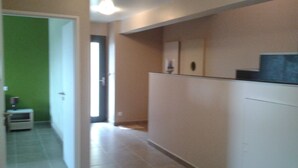 A corridor with a green wall on one side and a beige wall on the other, leading to a door. - Newly built, secluded villa with a pool—sleeps 8 to 12—sauna—air conditioning (Saint-Julien-De-Peyrolas)