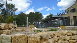 A modern outdoor area with a pool, stone walls, and umbrellas. - Newly built, secluded villa with a pool—sleeps 8 to 12—sauna—air conditioning (Saint-Julien-De-Peyrolas)