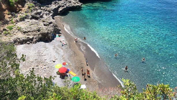 A beach with clear turquoise water, rocky cliffs, and people swimming and sunbathing. - Villa in Maratea   Walking Distance From The Beach  CIN-IT076044C203105001 (Acquafredda,  Maratea)