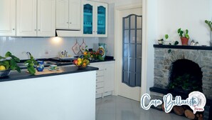 A modern kitchen with white cabinets, a black countertop, and a stone fireplace. - CASA BELLAVISTA ( “Bellavista” holiday home ) ……Where hospitality is at home (Furore)