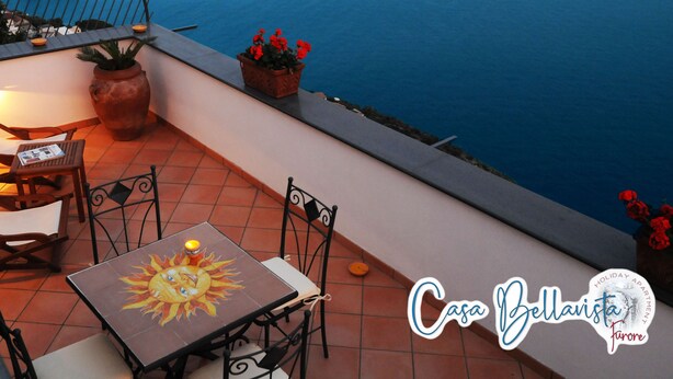 A terrace with a table and chairs, potted plants, and a view of the sea. - CASA BELLAVISTA ( “Bellavista” holiday home ) ……Where hospitality is at home (Furore)