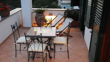Eine Terrasse mit Tisch, Stühlen, einer Topfpflanze und einer Lampe.