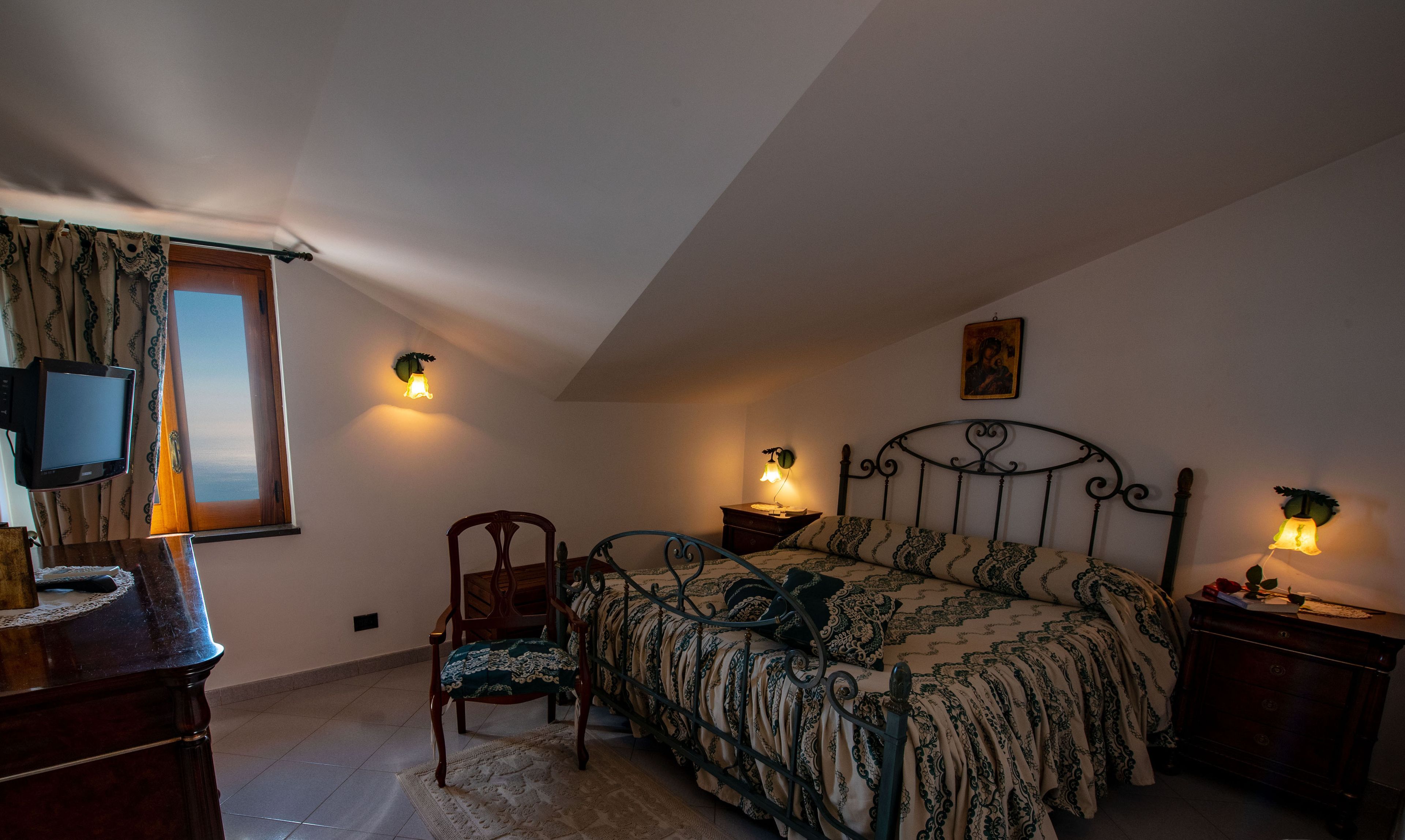 A bedroom with a bed, a chair, a desk, and a television.