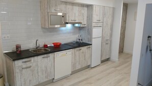 A modern kitchen with white cabinetry, a black countertop, and a stainless steel sink. - Enchanted land of Asturias (Gijón)