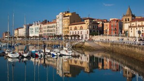 A marina with boats docked, a bridge, and historic buildings along the waterfront. - Enchanted land of Asturias (Gijón)
