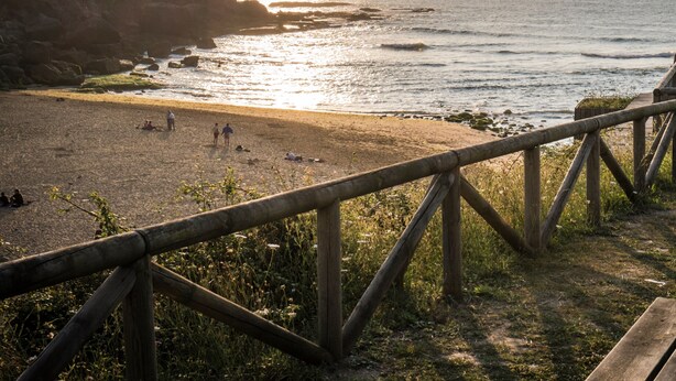 A beach with a wooden fence, rocky cliffs, and the ocean. - Enchanted land of Asturias (Gijón)