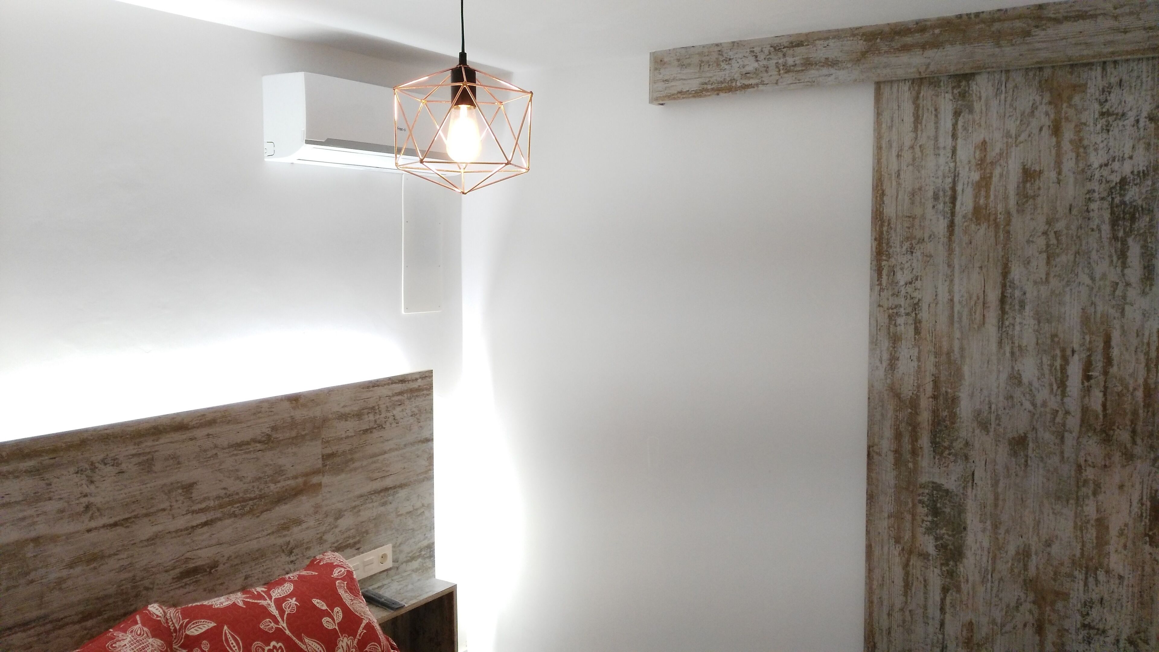 A modern room with a geometric pendant light, a wooden accent wall, and a rustic wooden door.