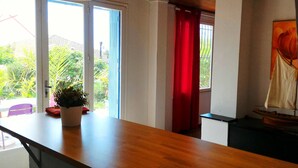 A room with a wooden table, a potted plant, a red curtain, and a sailboat model.