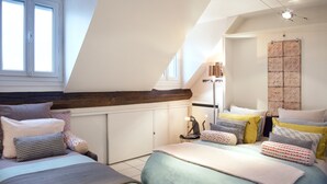 A bedroom with a sloped ceiling, a bed with multiple pillows, a nightstand, and a wall-mounted cabinet. - Studio With a Nice View of Paris - Luxury Building in the Heart of the Marais (Paris)