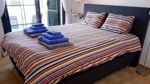 A bed with a striped bedspread, two pillows, and a stack of folded towels. - Altea - family apartment !! Close to the sea. (Altea)