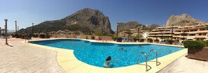 A swimming pool with clear blue water, surrounded by lounge chairs and a mountainous backdrop. - Altea - family apartment !! Close to the sea. (Altea)