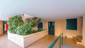 A spacious indoor area with a tiled floor, a staircase, a green railing, and a wall with climbing plants. - Altea - family apartment !! Close to the sea. (Altea)