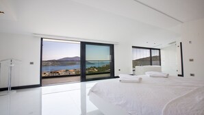 A modern bedroom with a large bed, a bathtub, and a balcony with a city view. - Villa Tyra ultra modern luxury 5 bedroom villa with stunning sea views (Kalkan, Kas)