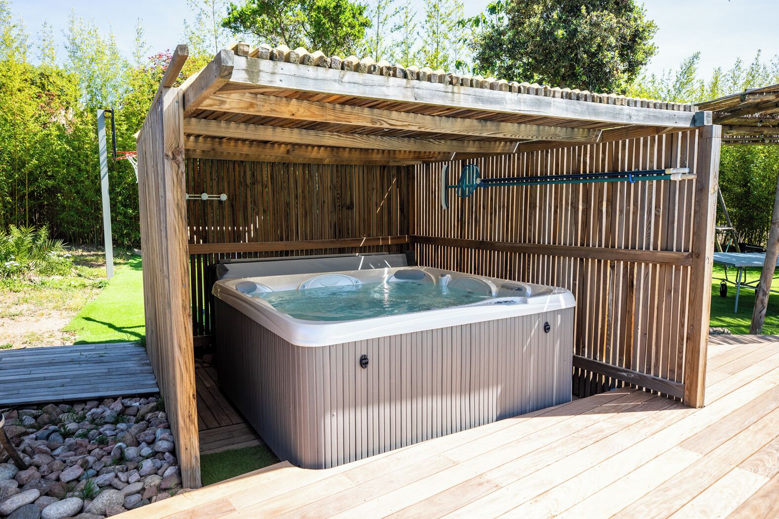 A hot tub in a wooden outdoor setting with a pergola overhead.