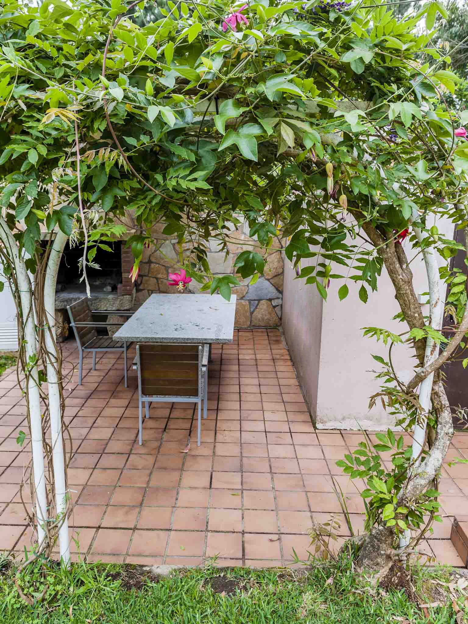 A patio with a table and chairs, surrounded by a stone wall and greenery.