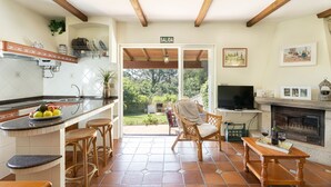 A kitchen with a tiled backsplash, wooden beams, a bar area with stools, a dining table, a television, and a fireplace. - House 7 minutes walk from the beach with garden and pool (La Coruña)