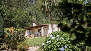 A stone house with a tiled roof, surrounded by lush greenery and a garden with various plants and flowers. - House 7 minutes walk from the beach with garden and pool (La Coruña)
