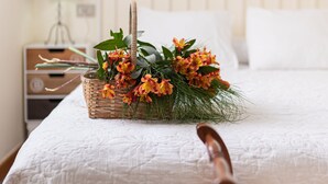 A neatly made bed with a white quilt, a wicker basket with flowers, and a round mirror on the wall. - House 7 minutes walk from the beach with garden and pool (La Coruña)