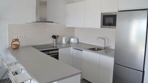Een moderne keuken met witte kastjes, roestvrijstalen apparatuur en een ingebouwde magnetron.