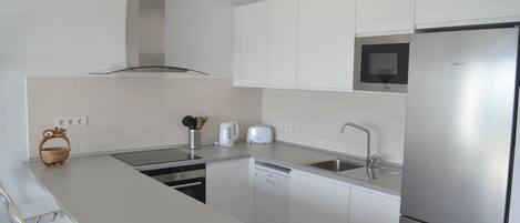 A modern kitchen with white cabinets, stainless steel appliances, and a built-in microwave.