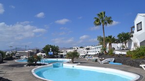 Een zwembadgedeelte van een resort met meerdere zwembaden, ligbedden en palmbomen.