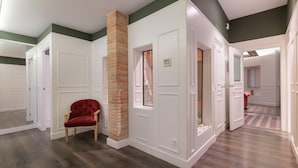 A hallway with white doors, a red chair, and a brick column. - Design and comfort on the Rambla (Barcelona)