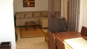 Una sala de estar con un sofá, una mesa de centro y una mesa de comedor con sillas.