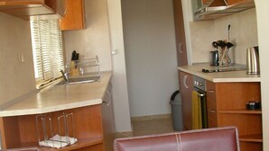Cocina compacta con armarios de madera, horno empotrado y comedor con mesa y sillas.