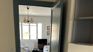 A room with a bed, a TV, and a dining area with chairs and a table.