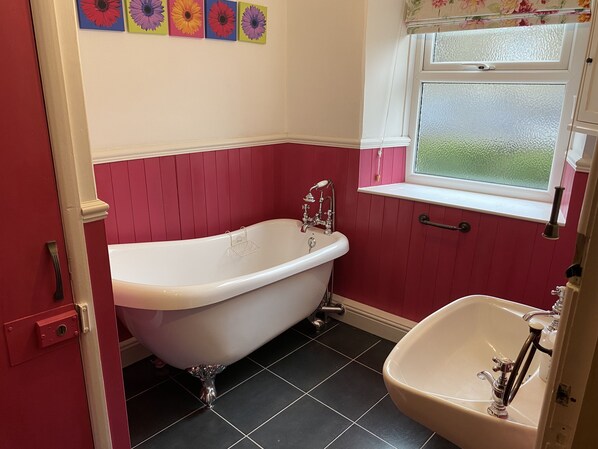Een badkamer met een vrijstaand bad, een wastafel en een raam met uitzicht.
