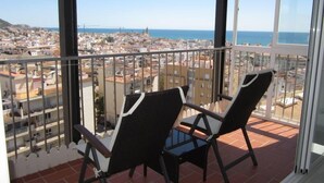 A balcony with two chairs, a view of a coastal cityscape, and a clear sky. - Sitges: Apartment/ flat - SITGES (Sitges)