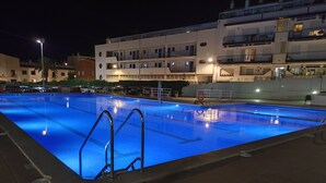 A swimming pool with a tiled deck and metal ladders. - Sitges: Apartment/ flat - SITGES (Sitges)