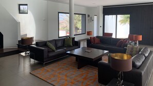Ein modernes Wohnzimmer mit zwei schwarzen Sofas, einem Couchtisch und einem gemusterten Teppich.