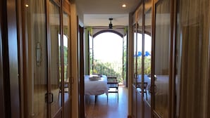 Un couloir avec des portes en bois donnant sur un balcon équipé d’un lit et d’un espace salon.