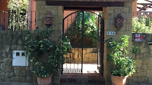 Un bâtiment en pierre avec un toit en tuiles, une porte et des plantes en pot.