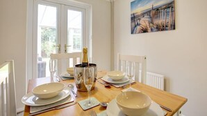 Une table à manger dressée pour quatre personnes, avec une bouteille de champagne, des bols et des verres à vin.