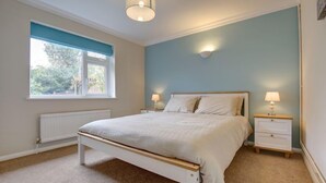 Une chambre avec un lit simple, deux tables de chevet, une fenêtre donnant sur un paysage agréable et un luminaire au plafond.
