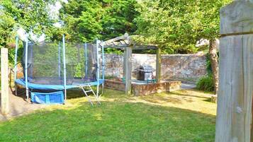 Enjoy a backyard retreat with a trampoline and barbecue area, surrounded by a fence and a charming pergola.