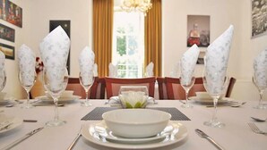 A dining table set with white plates, bowls, and glasses, with napkins folded in a decorative style.