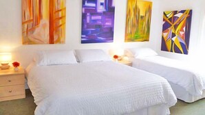 A hotel room with two beds, white bedding, and three large abstract paintings on the wall.
