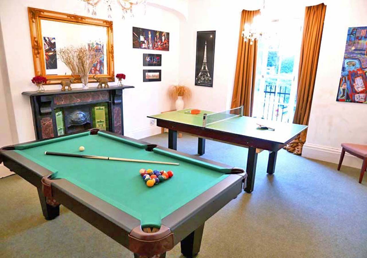 A pool table with balls, a billiards table, and a fireplace with decorative items.