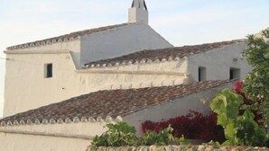 A white building with a tiled roof and a stone wall. - Charming house in the old part of Sant Lluis, near the mill (Sant Lluís)