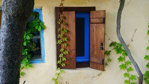 Un bâtiment rustique avec une porte en bois et une fenêtre ornée de volets bleus.