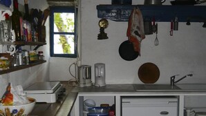 Une cuisine compacte avec un sol carrelé en pierre, un petit réfrigérateur et divers ustensiles et appareils de cuisine.