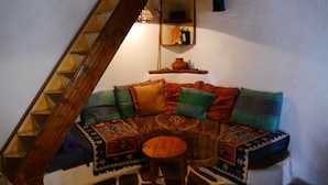 Un coin salon accueillant avec un escalier en bois, une petite table et une étagère ornée d’objets décoratifs.