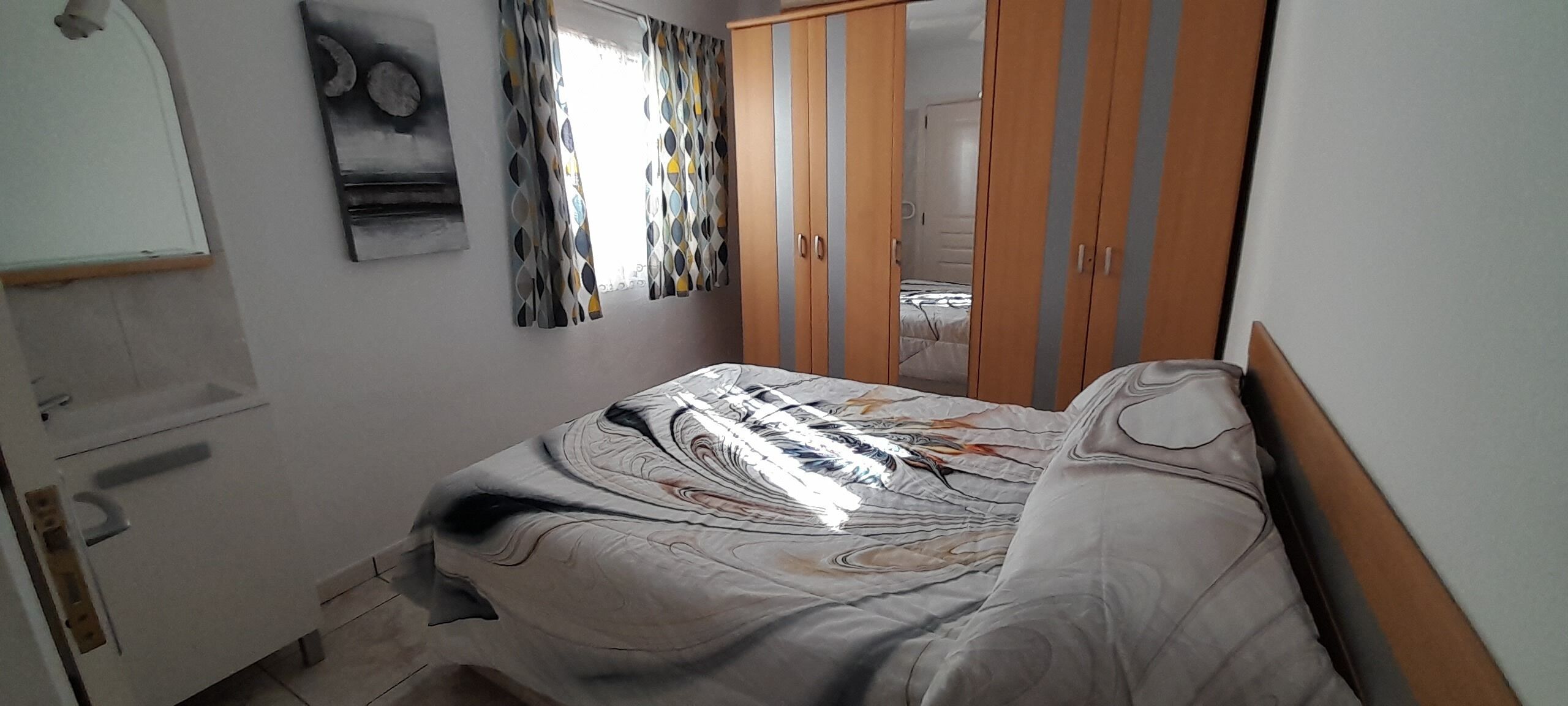 A bedroom with a bed, a wardrobe, and a mirror.