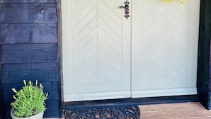 A door with a chevron pattern, a sign reading "Mulberry Cottage", a wreath, and a potted plant on the porch.