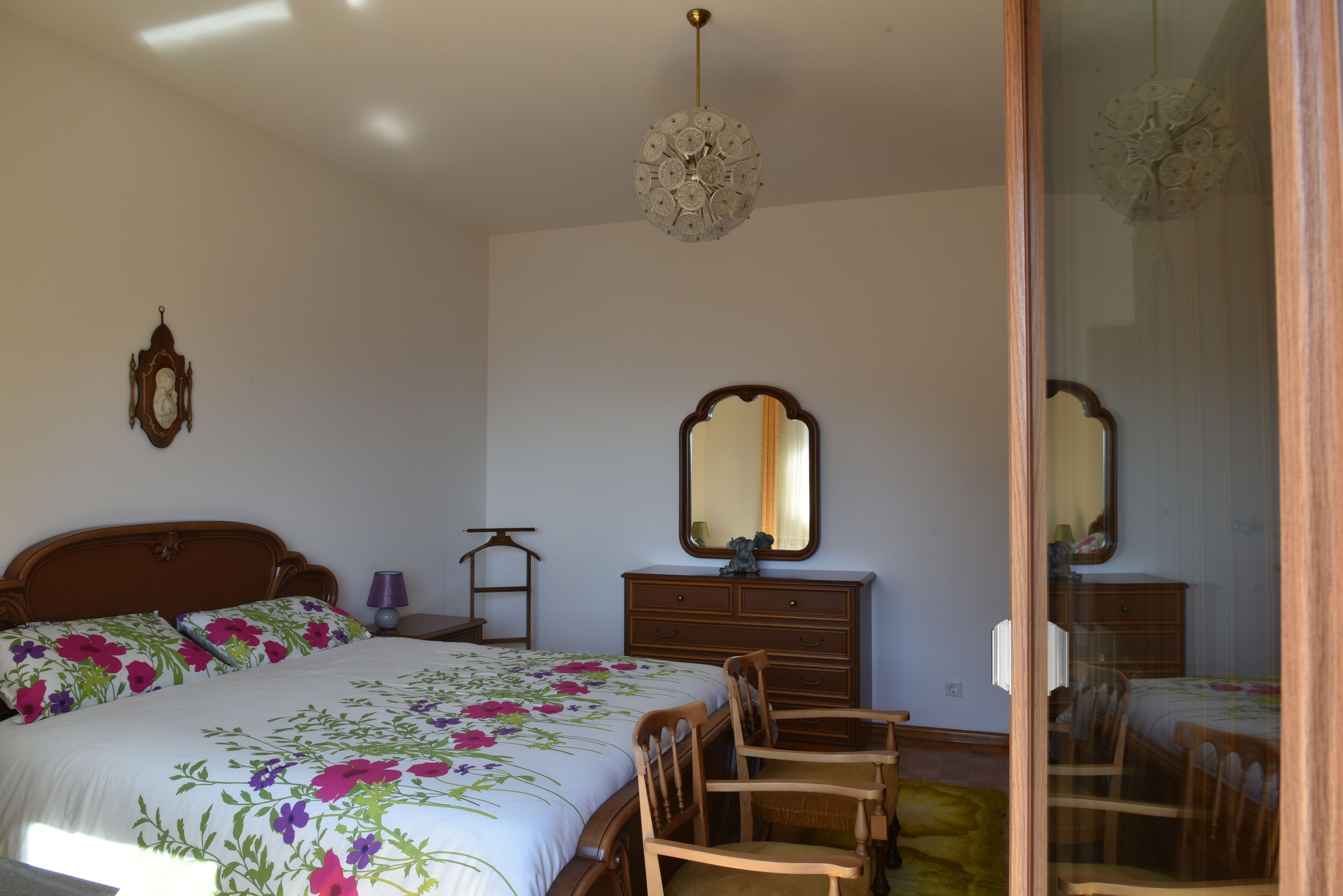 Une chambre à coucher avec un lit, une commode, un miroir et des chaises.