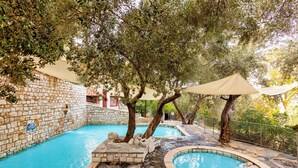 Una piscina exterior con muros de piedra y árboles.