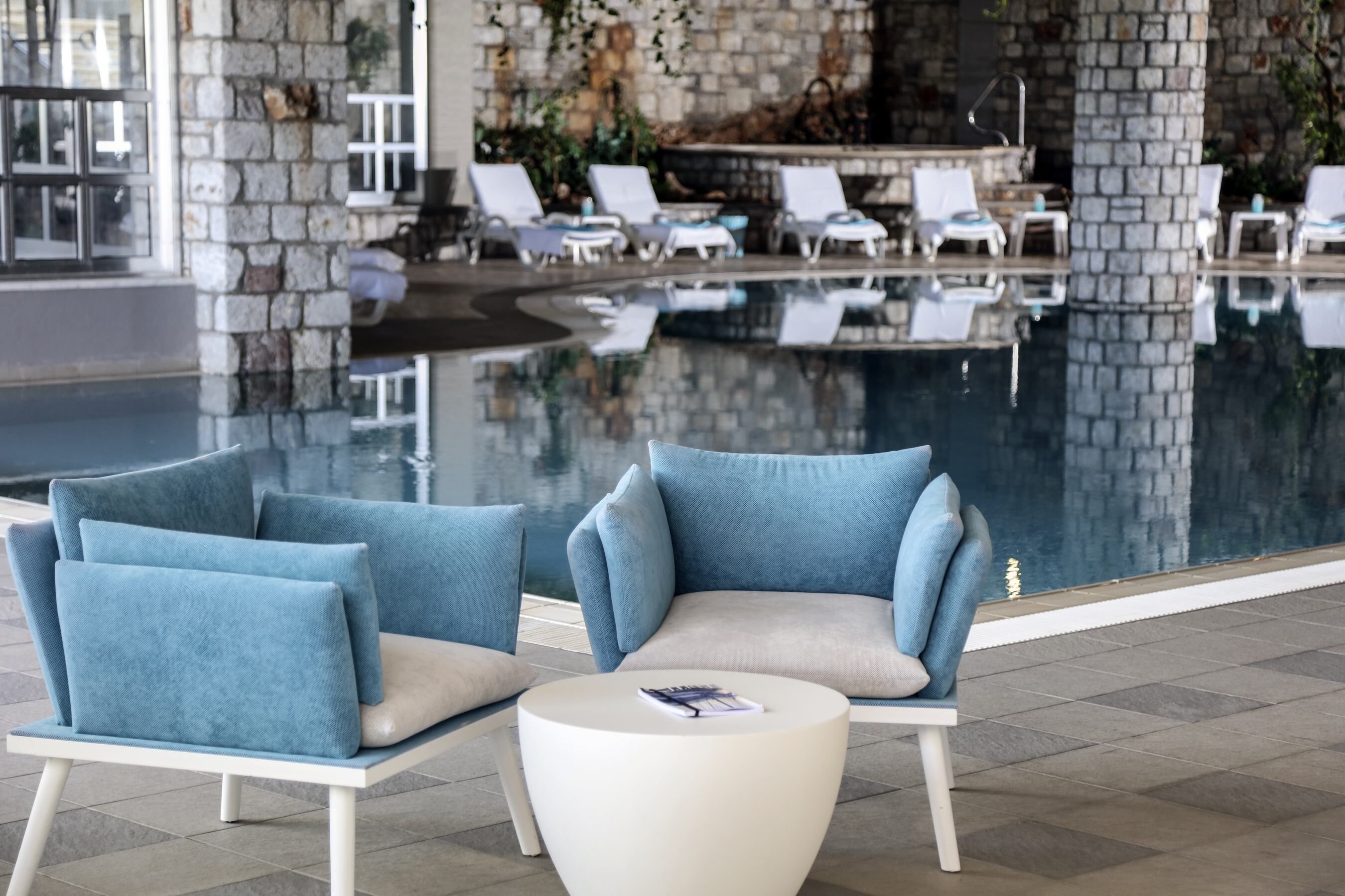 A poolside area with lounge chairs and a white table.